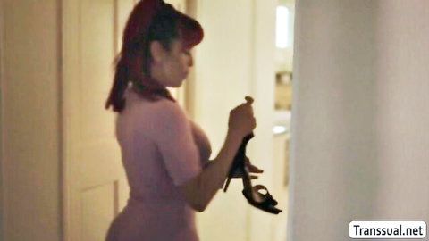 Brunette trans babe in tight pink dress holds black high heel shoe teasingly