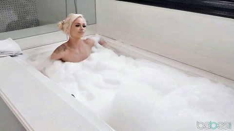 Blonde tattooed babe nude in foamy bubble bath, suds teasing her perky tits and pussy