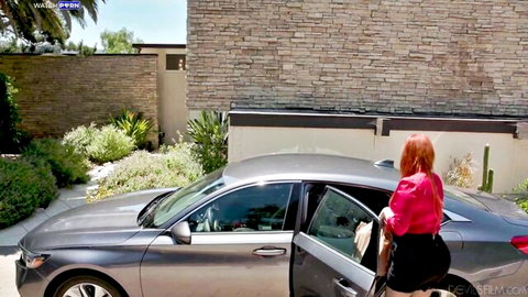 Lauren Phillips redhead in pink top and skirt by car, teasing outdoor pose