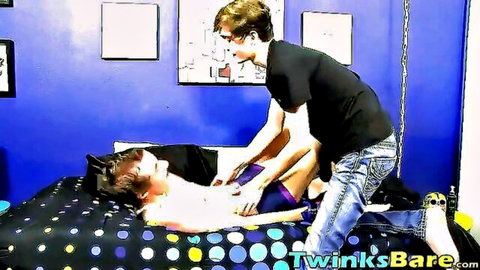 Dominant twink in black tee holds legs of nude twink to bareback fuck his ass on bed