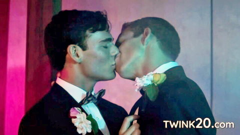 Two handsome young gay twinks in tuxedos passionately kissing on stage