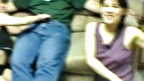 Amateur Asian babe in tank top smiling with two guys on couch in threesome setup