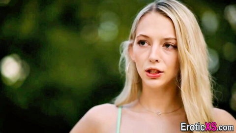 Petite blonde Lily Larimar smiling with red lips outdoors in green top