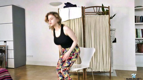 Bella Breeze squatting teasingly in tank top and patterned pants