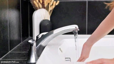 Redhead babe's wet hand under running faucet filling bathtub in steamy bathroom