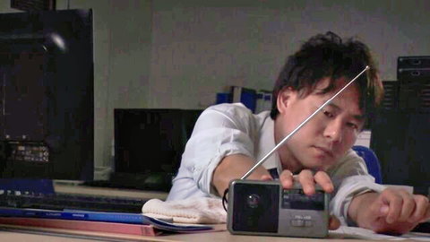 Asian office worker secretly recording with camcorder in dim-lit room
