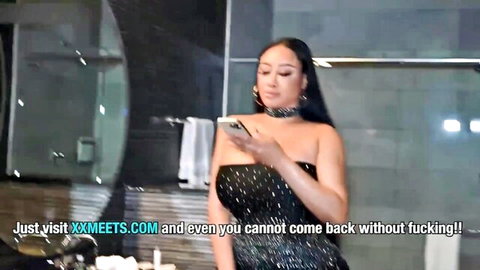 Jennifer White in sparkly black dress, teasing with phone in hotel bathroom