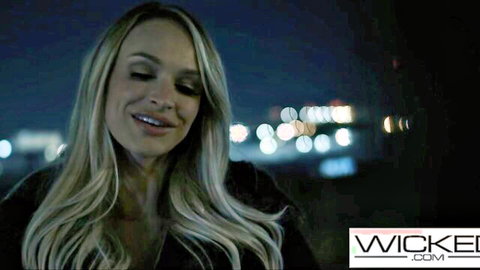 Emma Hix smiling seductively at night with city lights background