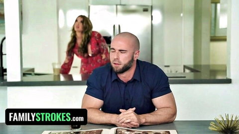 Curvy blonde stepdaughter in red dress watches stepdad at kitchen table