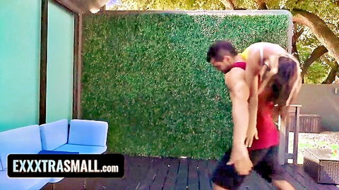 Muscular stud carries petite tanned teen with small tits topless on his back outdoors