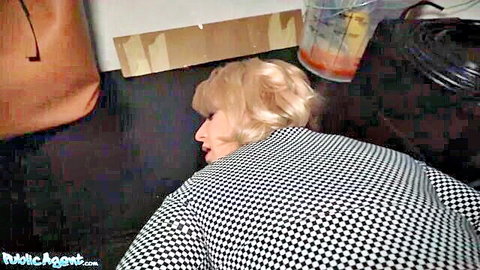 Blonde woman in checkered dress lying passed out on kitchen floor near orange drink