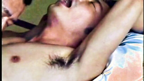 Asian man lying back with shirt open, partner leaning in for intimate climax help