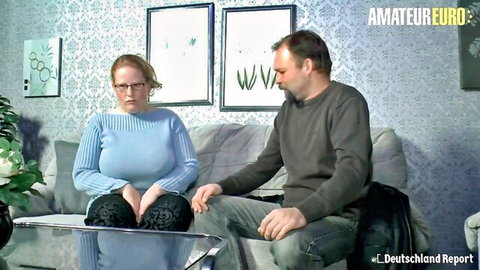 European BBW redhead with glasses in blue sweater sits with man on couch, amateur tease
