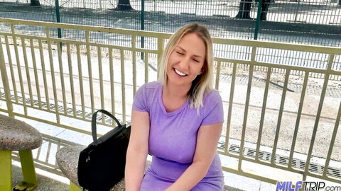 Blonde MILF Quinn smiling in purple dress on outdoor vacation
