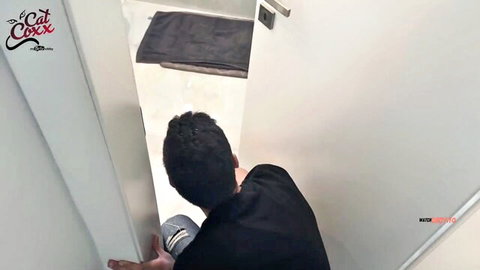Voyeur guy in black shirt and jeans crouching to peek through open bathroom door POV