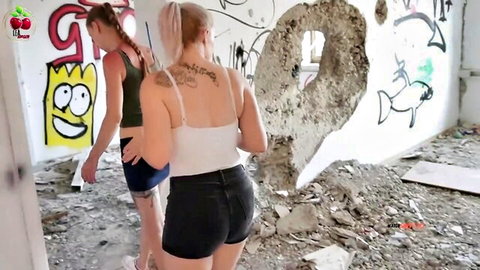 Two sexy blondes in tight shorts tease juicy asses walking away in graffiti-covered abandoned building
