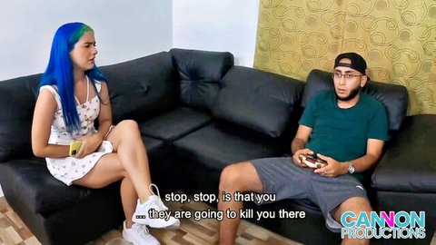 Colombian babe with blue hair in floral dress talks to gamer guy on couch