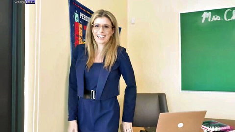 Cory Chase as sexy blonde teacher in blue dress and glasses, smiling