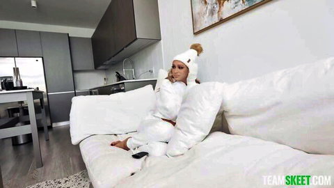 Seductive babe in white beanie and tracksuit lounging teasingly on couch