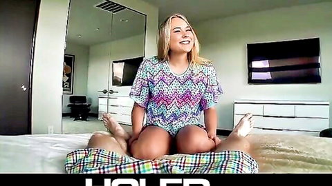 Smiling blonde teen spreads legs wide in colorful romper teasing tight pussy on bed