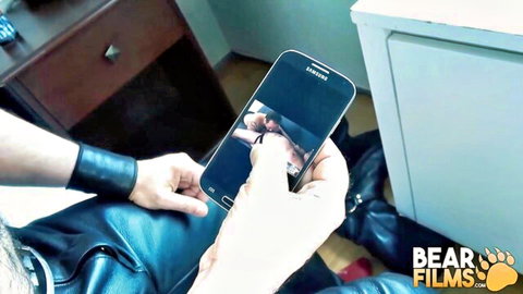 Hairy bear in leather pants watches gay rimjob porn on Bear Films phone video