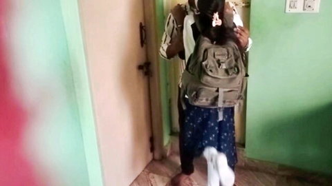 Indian schoolgirl in uniform skirt and backpack stands teasingly in bedroom doorway