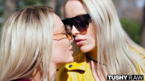 Two sexy blondes in sunglasses leaning in for a passionate kiss outdoors