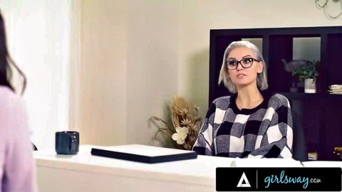 Blonde therapist with glasses in checkered sweater faces young Asian woman in purple top during lesbian office counseling