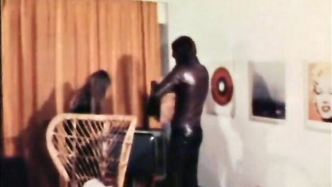 Vintage retro babe kneels before shirtless black stud's bulging cock in steamy couple scene