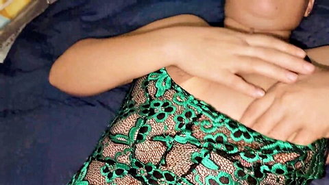 Seductive woman in green lace top with deep cleavage lying on bed