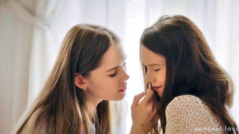 Two young brunette lesbians sensually fingering each other's lips in passionate erotic tease