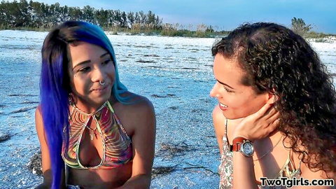 Two bikini babes with cleavage flirting intimately on sunny beach