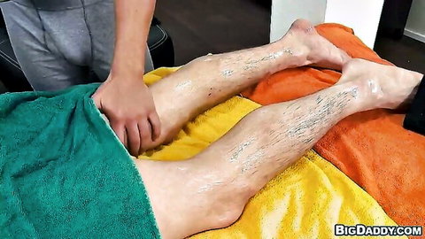 Gay masseur oils and massages hairy nude man's thighs under green towel