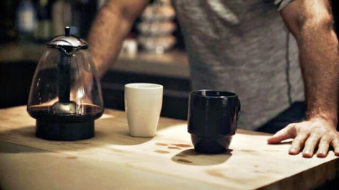 Muscular man's arm leaning over kitchen counter with glowing teapot and mugs