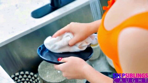 Petite blonde teen in tight orange top washing dishes exposing sideboob in kitchen