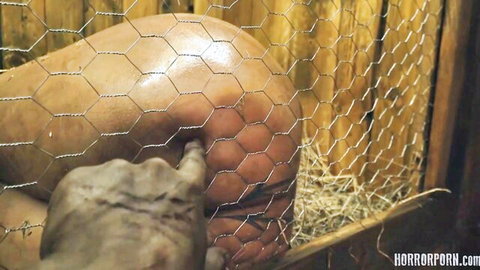 Zombie hand gropes huge pale bare ass through wire fence in horror barn