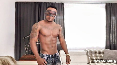 Muscular tattooed masked black guy shirtless in low-hanging ripped jeans teasing bulge