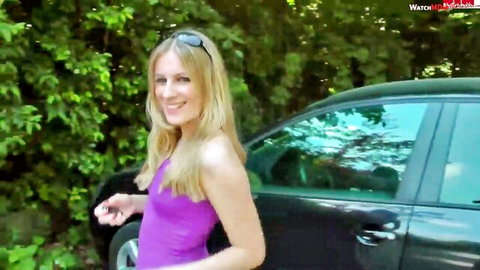 Blonde babe in tight purple dress showing cleavage posing by black car outdoors