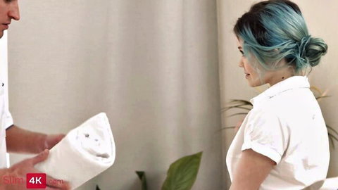 Teal-haired skinny babe in white shirt posed with man holding towel in bedroom