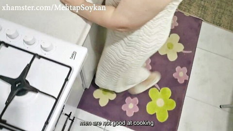 Southeast Asian woman in tight white dress bends over kitchen stove teasing round ass