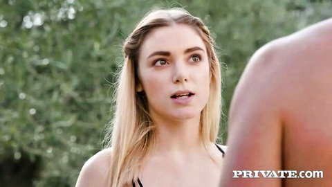 Blonde babe in black bikini top stares surprised at muscular man's bare back outdoors