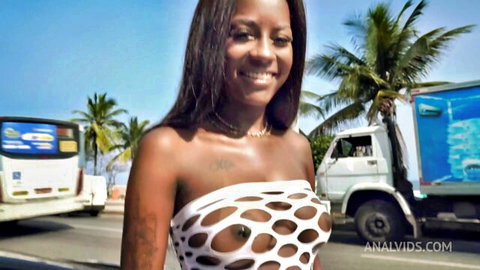 Smiling ebony babe exposes small tits and dark nipples through sheer polka-dot mesh top on public street
