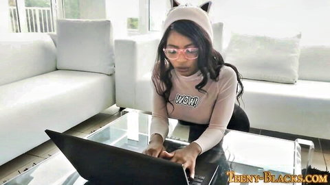 Ebony teen in cat ears and glasses teasing on laptop in pink top
