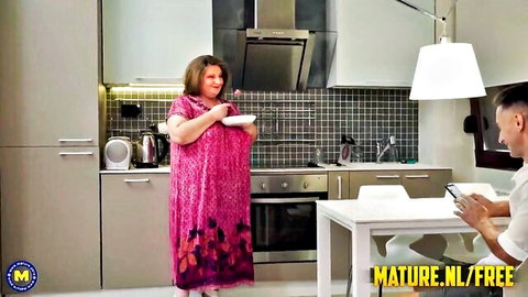 Jana curvy mature in pink dress teases younger stud in kitchen