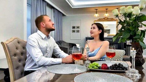 Romantic couple toasting wine glasses at elegant dinner table with fruit and roses