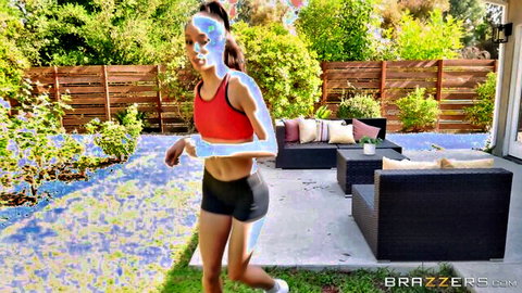 Sexy young jogger in tight red sports bra and black shorts running outdoors on patio