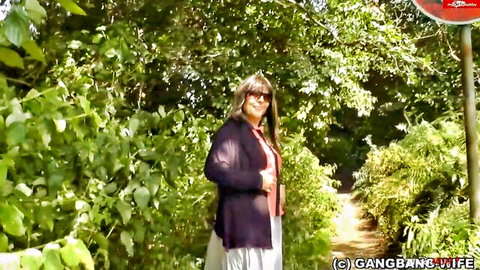 Blonde mature wife smiling in casual outfit at outdoor Autobahn rest stop