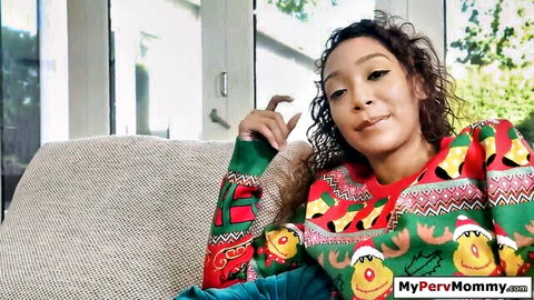 Curly-haired ebony MILF in festive Christmas sweater smiling seductively on couch for MyPervMommy