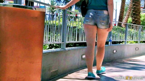 Jodi Taylor in tight denim shorts and backpack on beach promenade