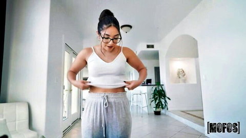 Petite brunette teen in glasses lifts white tank top teasing flat stomach and small tits bulge